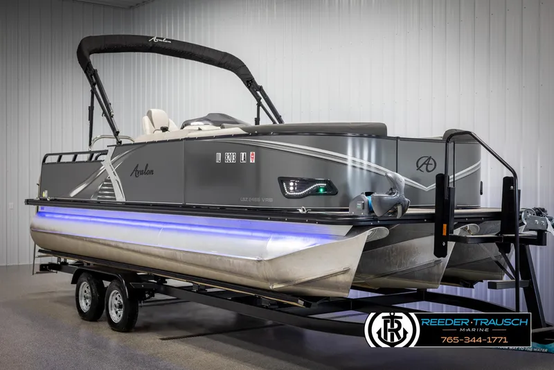 Slide: The Image of 2021 Avalon LSZ VRB pontoon boat on trailer in showroom with blue underglow lighting. - 1