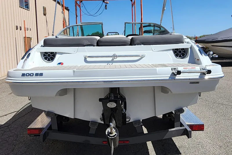 Slide: The Image of 2024 Crownline 200SS boat on trailer, rear view, in a marina setting. - 2