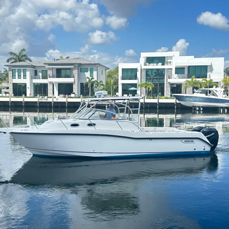 Slide: The Image of 2006 Boston Whaler 305 Conquest boat on calm water, modern waterfront homes in background. - 0