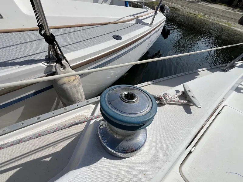 Slide: The Image of 1982 Catalina 27 sailboat deck with winch and rope, docked by the water. - 11