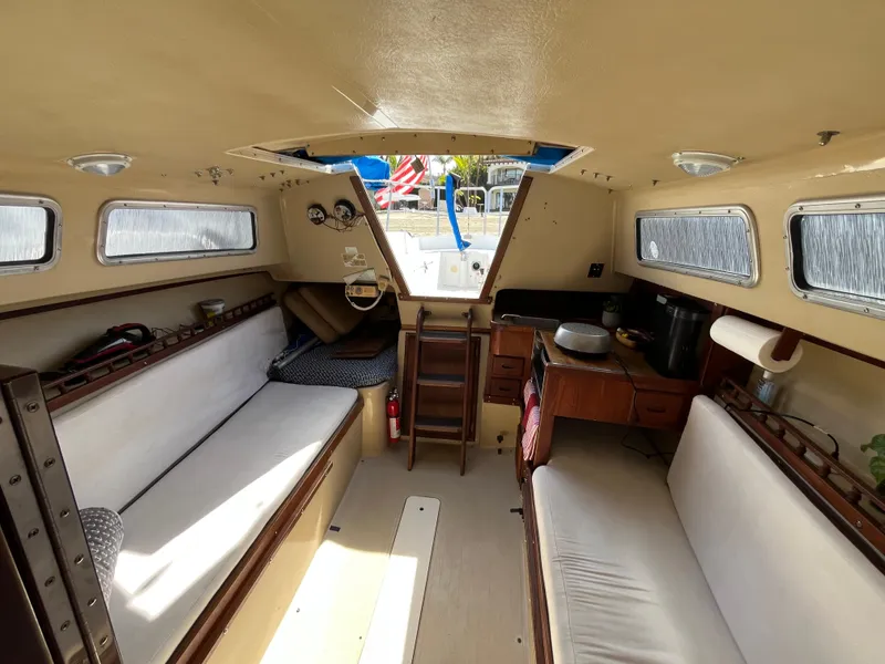 Slide: The Image of Interior of a 1982 Catalina 27 sailboat, featuring seating and compact kitchen area. - 13