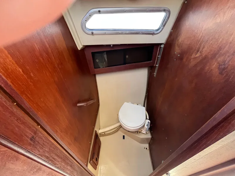 Slide: The Image of 1982 Catalina 27 sailboat bathroom with wooden interior and compact toilet. - 22