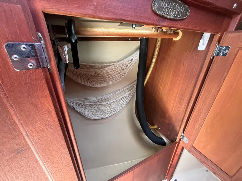 Slide: The Image of Interior storage compartment of 1982 Catalina 27 sailboat with wooden finish and netting. - 25
