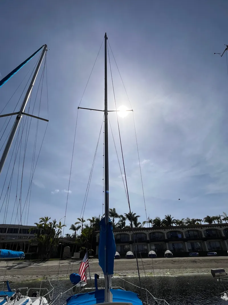 Slide: The Image of Sailboat mast of 1982 Catalina 27 against a sunny sky, near a beach resort. - 3