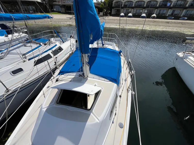 Slide: The Image of 1982 Catalina 27 sailboat with blue cover docked in marina. - 4