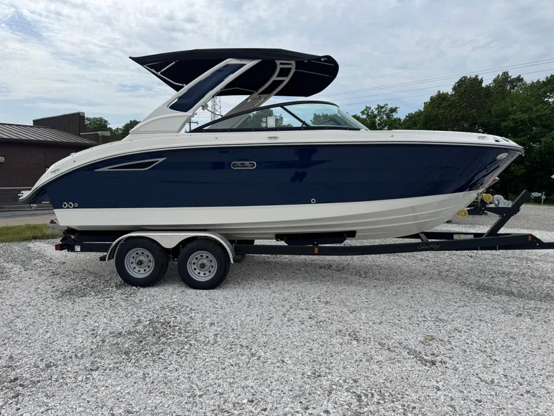 The Image of 2025 Sea Ray SDX 250 boat on trailer, blue and white design, parked outdoors. - 1