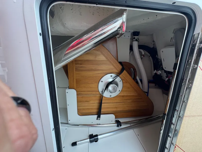 Slide: The Image of Storage compartment inside 2025 Sea Ray SDX 250 boat, featuring wooden panel and equipment. - 22