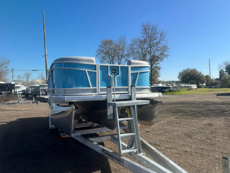 Slide: The Image of 2025 Godfrey Monaco 235 DFL Tritoon on trailer, parked outdoors under clear blue sky. - 10