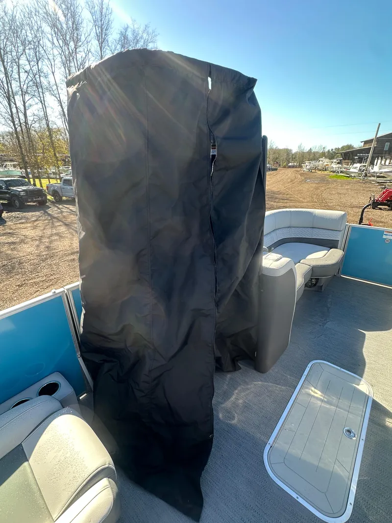 Slide: The Image of 2025 Godfrey Monaco 235 DFL Tritoon interior with covered console, sunny day. - 17