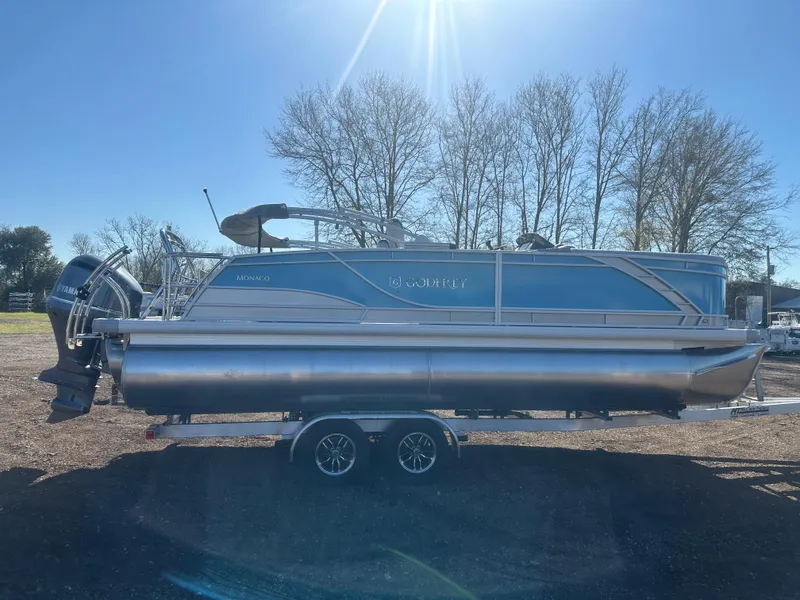 Slide: The Image of 2025 Godfrey Monaco 235 DFL Tritoon boat on trailer, parked outdoors. - 7