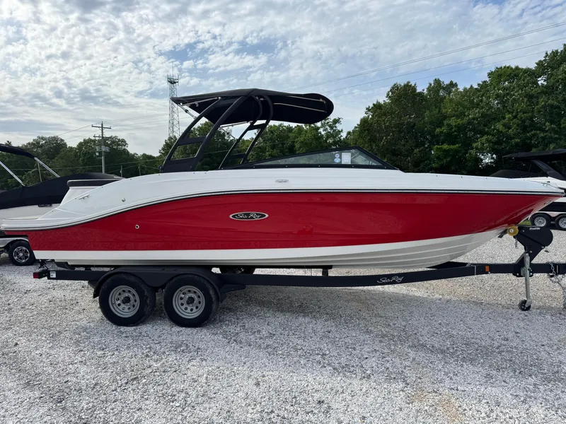 Slide: The Image of 2025 Sea Ray SPX 230 boat with red hull on a trailer, parked outdoors. - 2