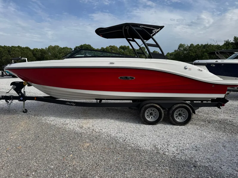 Slide: The Image of 2025 Sea Ray SPX 230 boat with red hull on a trailer, parked outdoors. - 6