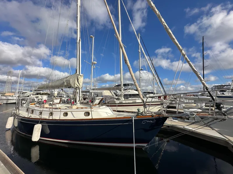 Slide: The Image of 1985 Shannon 43 Classic Cutter sailboat docked at marina under blue sky. - 1