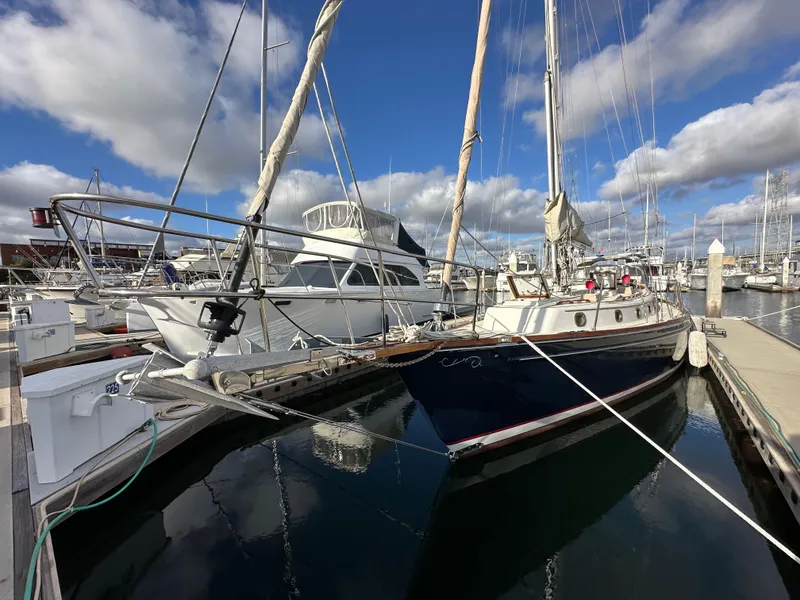 Slide: The Image of 1985 Shannon 43 Classic Cutter sailboat docked in a marina under a blue sky. - 14