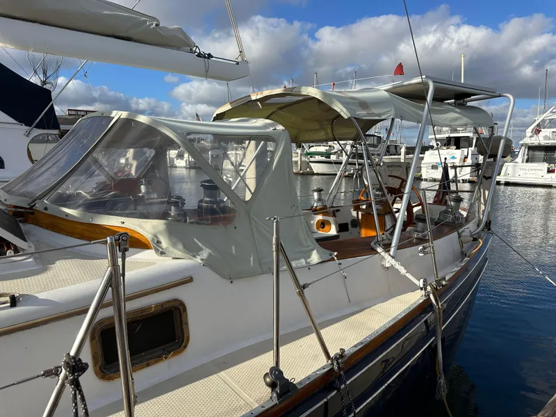 Slide: The Image of 1985 Shannon 43 Classic Cutter sailboat docked in marina, featuring protective canopy and clear skies. - 19