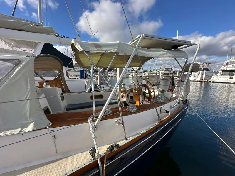 Slide: The Image of 1985 Shannon 43 Classic Cutter sailboat docked in a marina under a partly cloudy sky. - 20
