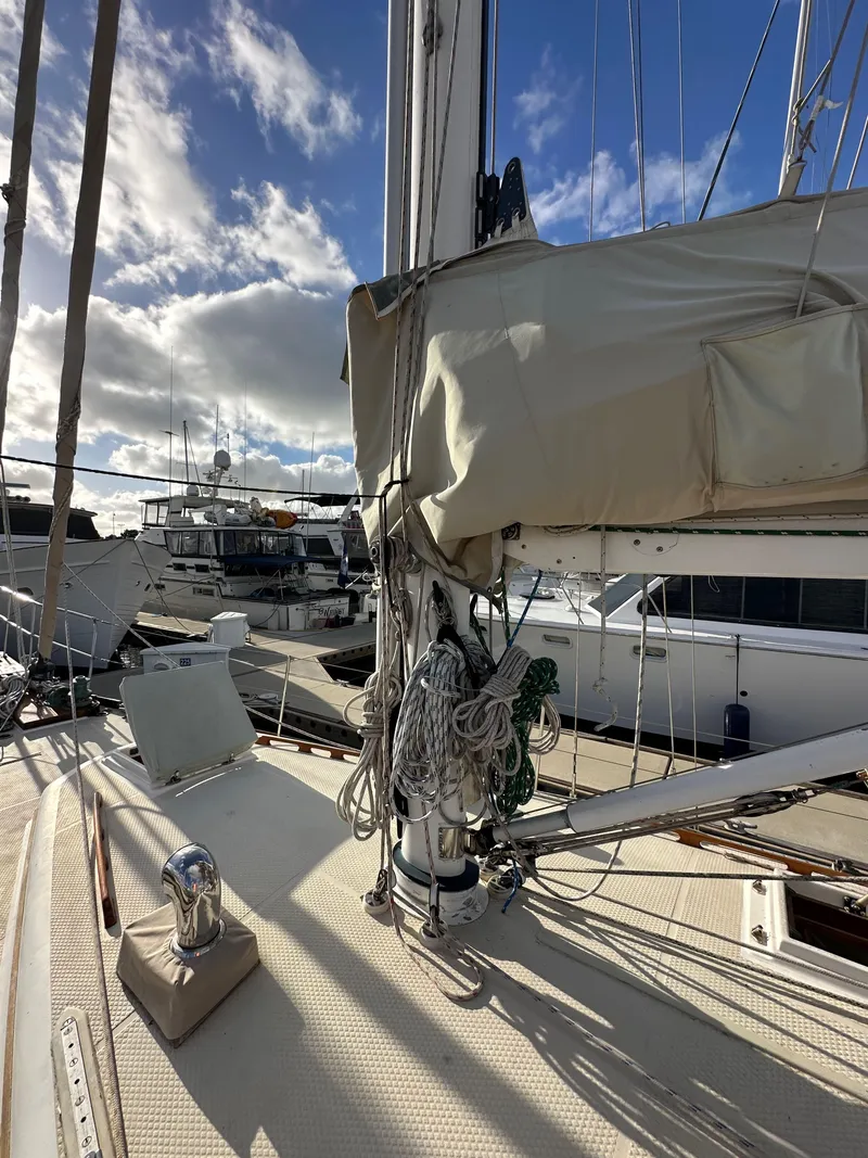 Slide: The Image of 1985 Shannon 43 Classic Cutter sailboat docked, with rigging and sails visible under a partly cloudy sky. - 26