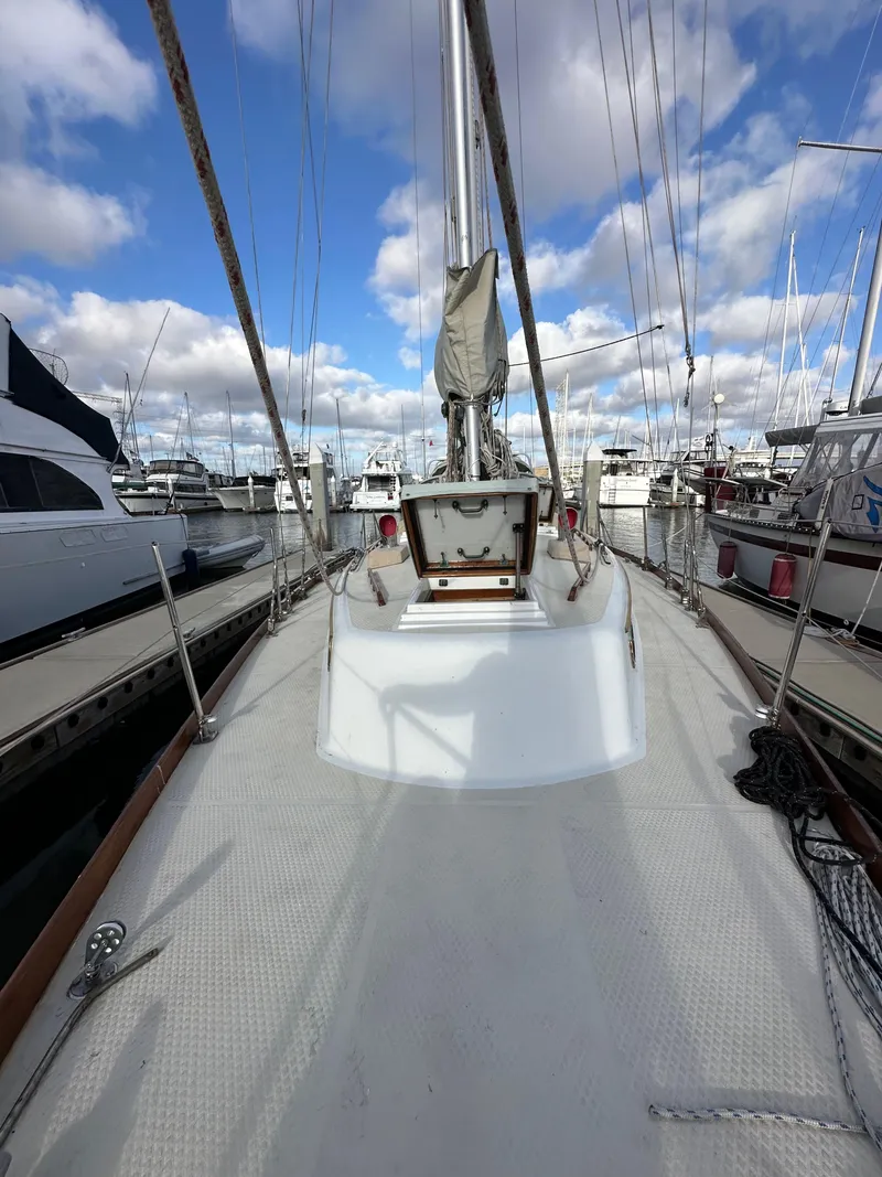 Slide: The Image of 1985 Shannon 43 Classic Cutter sailboat docked in a marina under a partly cloudy sky. - 31