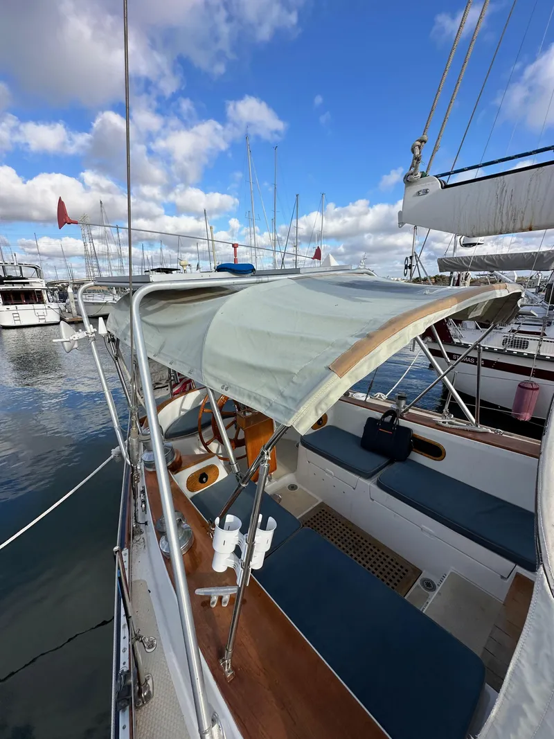 Slide: The Image of 1985 Shannon 43 Classic Cutter sailboat with canopy, docked in a marina under blue skies. - 36