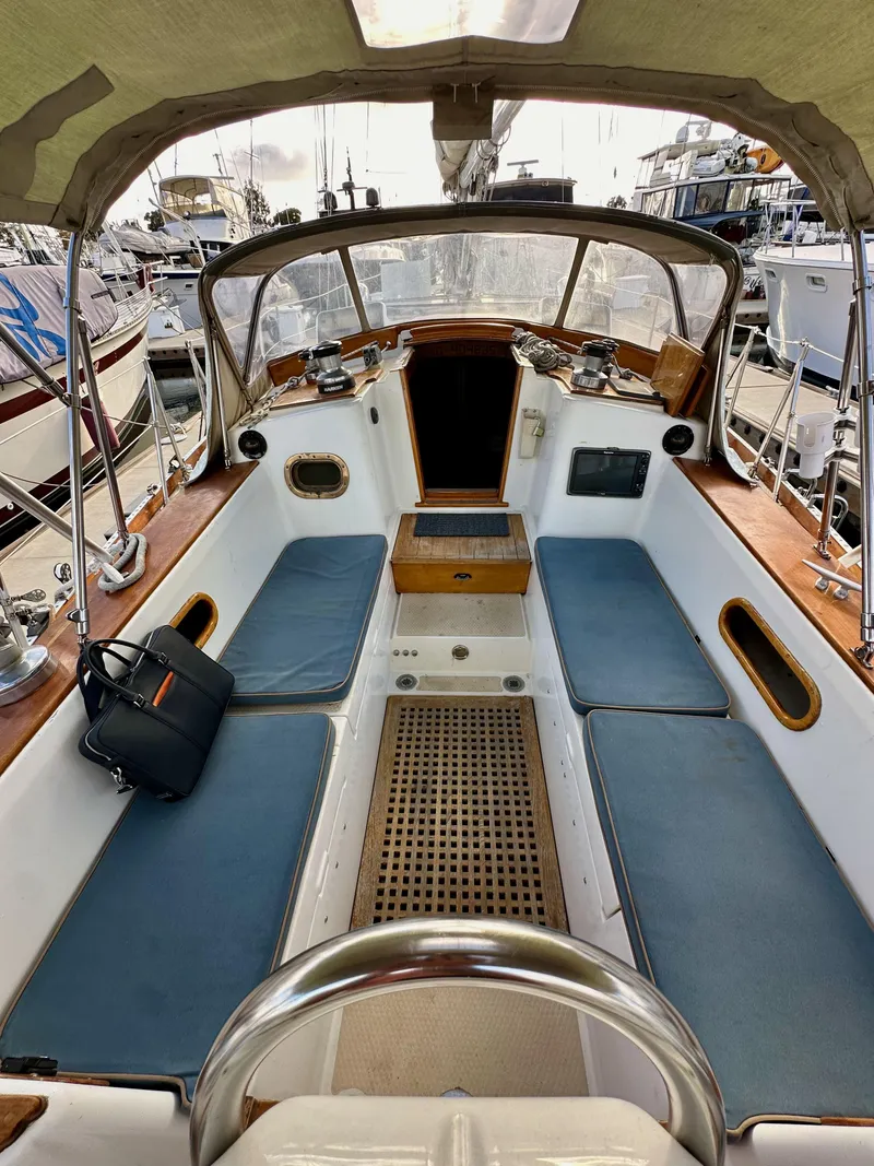 Slide: The Image of 1985 Shannon 43 Classic Cutter sailboat cockpit with blue cushions and wooden accents. - 44