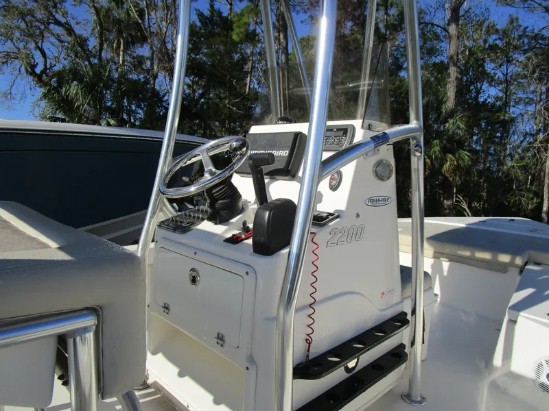 Slide: The Image of 2016 Pathfinder 2200 TRS boat console with steering wheel and controls, surrounded by trees. - 8