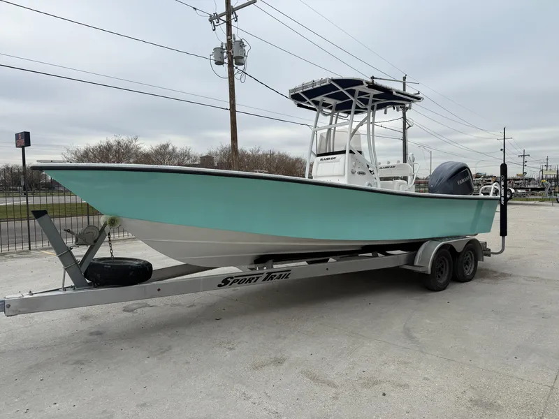 Slide: The Image of 2012 Blazer 2400 boat on trailer, light blue hull, parked outdoors. - 21