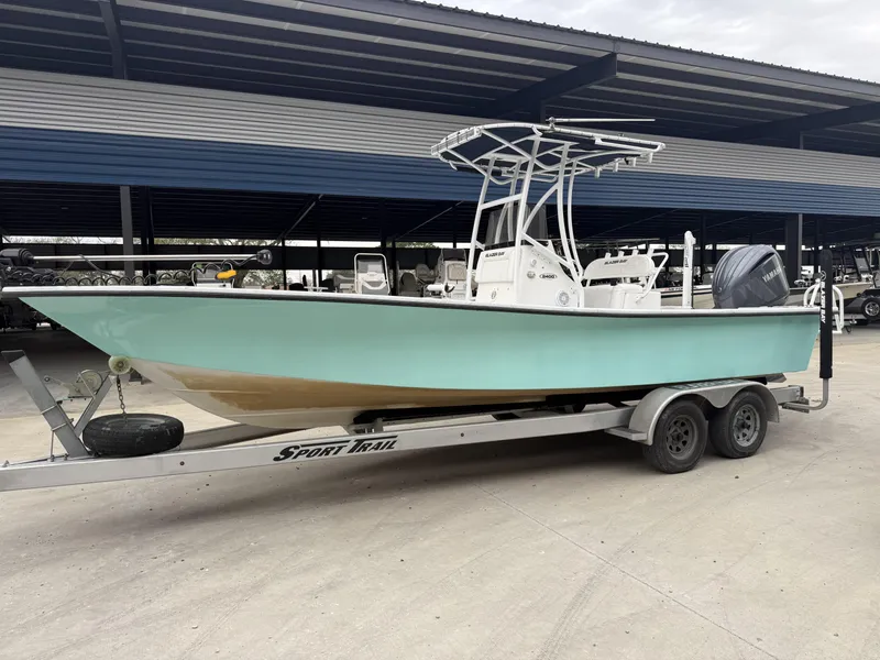 Slide: The Image of 2012 Blazer 2400 boat on trailer, light blue hull, parked under a metal canopy. - 8