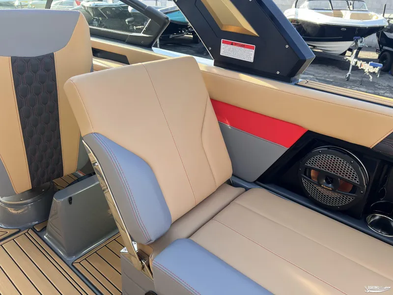 Slide: The Image of 2025 MasterCraft XT25 interior with beige and gray seating, red accents, and speaker system. - 15