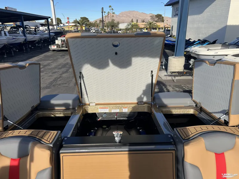 Slide: The Image of 2025 MasterCraft XT25 boat interior with open storage compartments in a marina setting. - 19