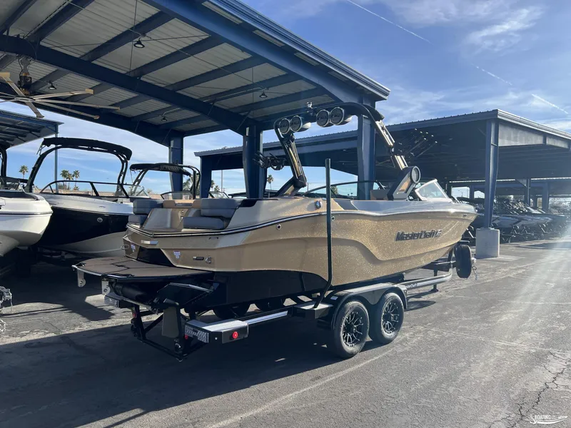Slide: The Image of 2025 MasterCraft XT25 boat on trailer in marina under blue sky. - 2
