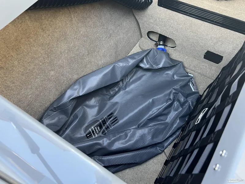 Slide: The Image of Storage compartment of 2025 MasterCraft XT25 boat with a gray bag inside. - 20