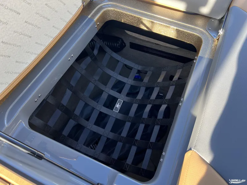 Slide: The Image of Storage compartment in 2025 MasterCraft XT25 boat with black netting. - 21