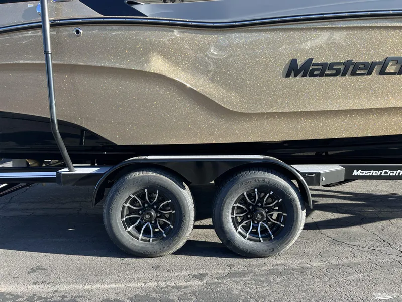 Slide: The Image of 2025 MasterCraft XT25 boat on trailer with stylish wheels and metallic finish. - 25