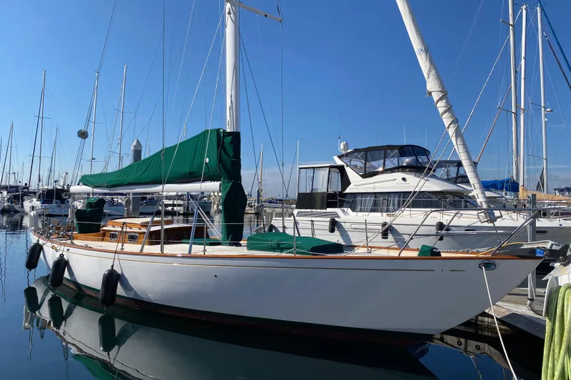 The Image of 1962 Cheoy Lee Custom sailboat docked in a marina, featuring green covers and clear blue skies. - 0