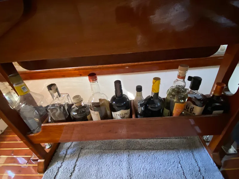 Slide: The Image of Bottles of liquor stored on a wooden shelf inside a 1962 Cheoy Lee Custom boat. - 20