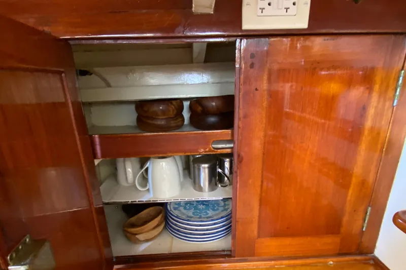 Slide: The Image of Wooden cabinet with dishes and mugs inside a 1962 Cheoy Lee Custom boat. - 28