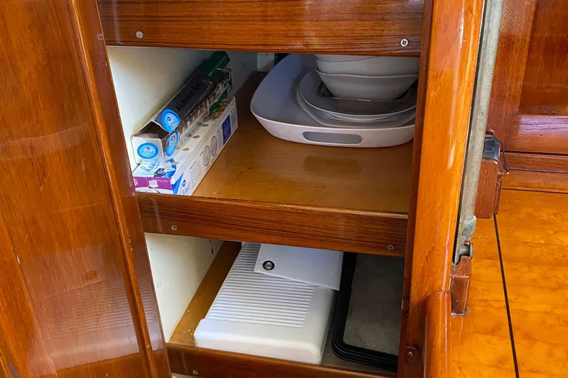 Slide: The Image of Wooden cabinet interior with shelves, kitchen items, and storage on a 1962 Cheoy Lee Custom boat. - 29