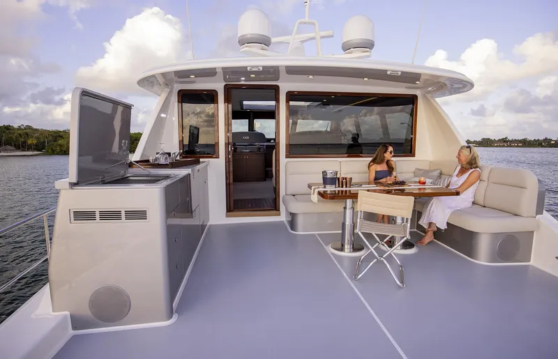 Slide: The Image of 2026 Grand Banks GB 85 yacht deck with seating area and two people relaxing. - 28