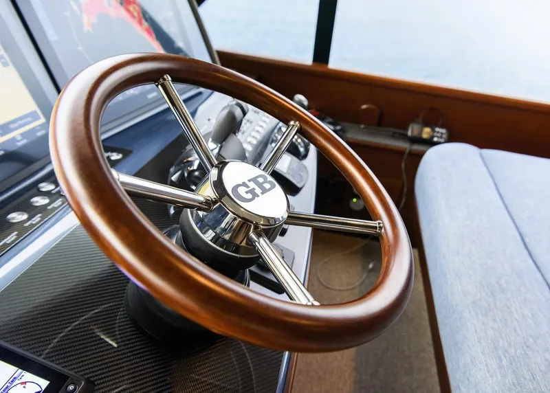 Slide: The Image of Steering wheel of 2026 Grand Banks GB 85 yacht, featuring wood and chrome design. - 4