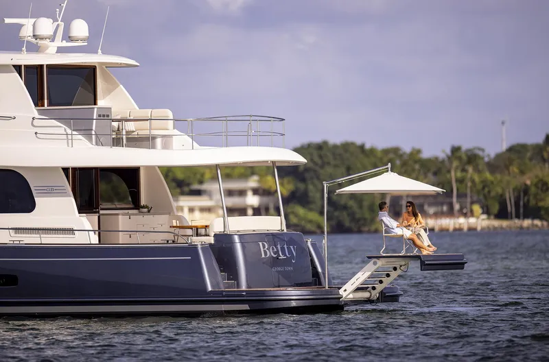 Slide: The Image of 2026 Grand Banks GB 85 yacht on water, featuring a luxurious deck with seating and umbrella. - 15