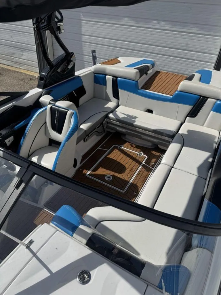 Slide: The Image of 2015 Nautique G21 boat interior with white and blue seating, wooden flooring. - 10