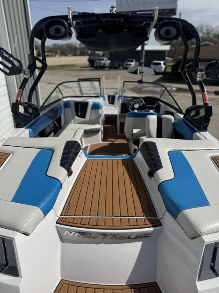 Slide: The Image of 2015 Nautique G21 boat interior with blue and white seating, wooden deck, and wakeboard tower. - 15