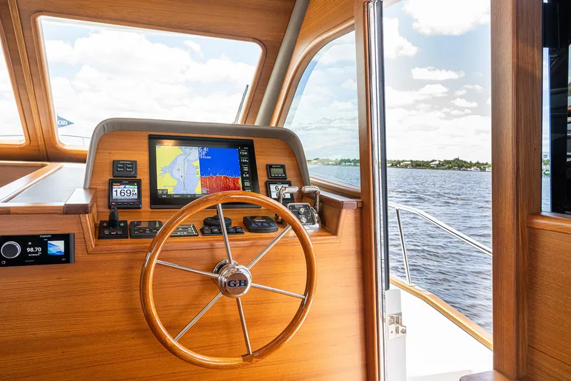Slide: The Image of 2026 Grand Banks GB 60 yacht helm with wooden steering wheel and navigation display. - 8