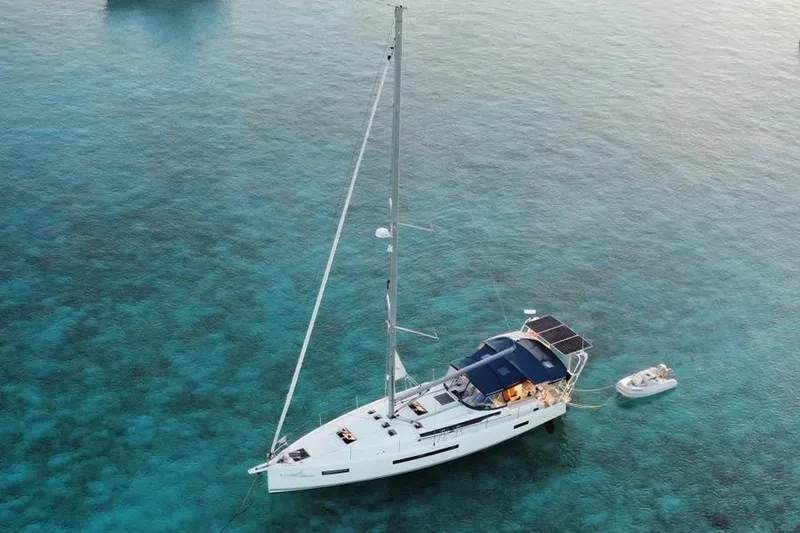 The Image of 2019 Jeanneau Sun Odyssey 490 sailboat anchored in clear turquoise waters. - 1
