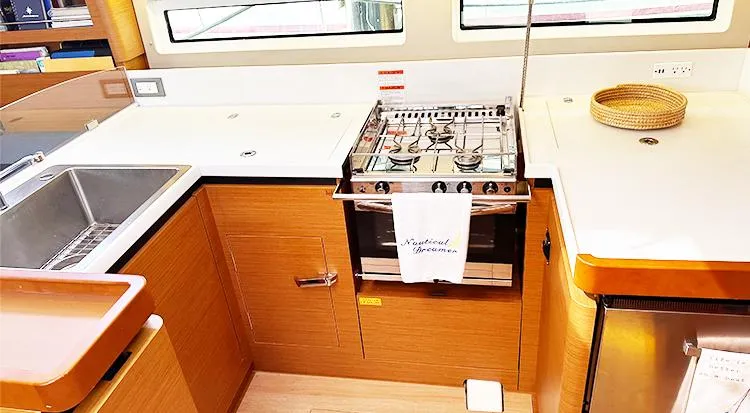 Slide: The Image of 2019 Jeanneau Sun Odyssey 490 yacht kitchen with stove, sink, and wooden cabinetry. - 22