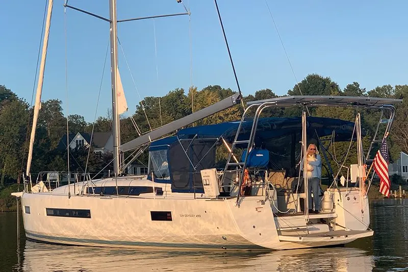 Slide: The Image of 2019 Jeanneau Sun Odyssey 490 sailboat on calm water with trees in the background. - 3