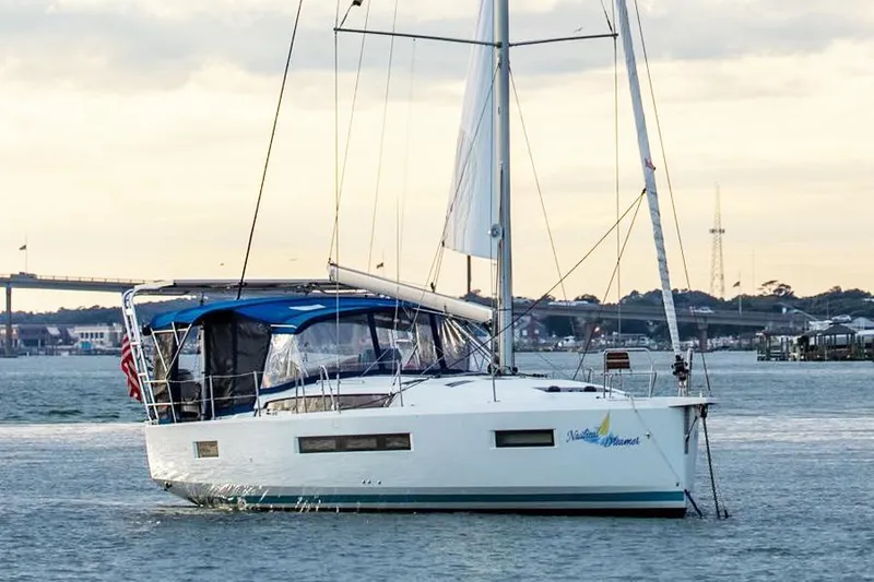 Slide: The Image of 2019 Jeanneau Sun Odyssey 490 sailboat on calm water, with scenic background. - 4
