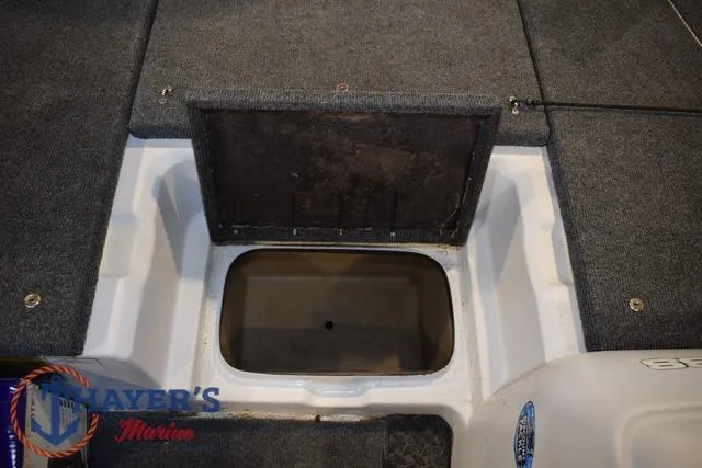 Slide: The Image of 1997 ProCraft 180 boat storage compartment with open hatch, gray carpet, and visible branding. - 9