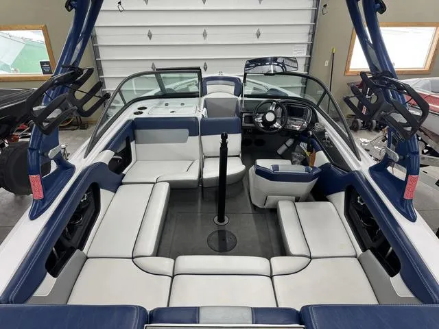 Slide: The Image of 2015 Nautique 200 boat interior with blue and white seating, steering wheel, and wakeboard racks. - 12