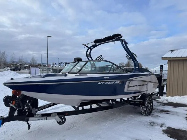 Slide: The Image of 2015 Nautique 200 boat on trailer in snowy setting, blue and white design. - 3